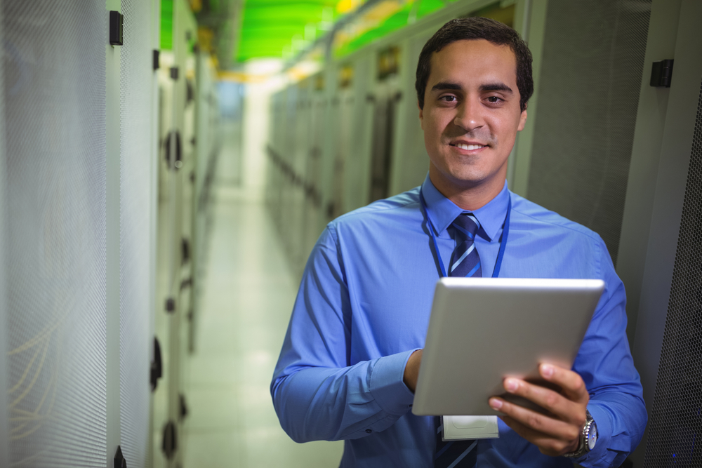Portrait of technician using digital tablet in hallway of server room